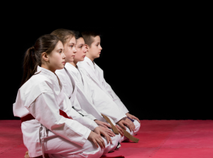 Barn som sitter i taekwondo dräkter.