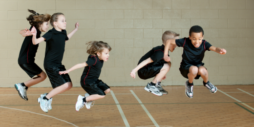 Fem barn i en gympasal hoppar samtidigt.