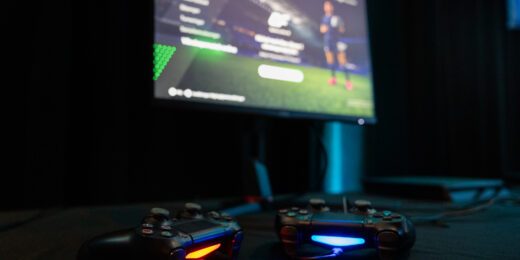 Två Playstation-kontroller framför en datorskärm som har spelet FC24 i gång.