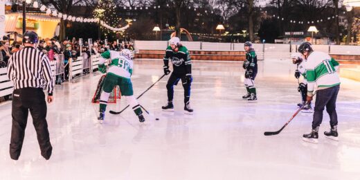 Personer spelar hockey på Lilla isbanan i Folkets park. En domare står i förgrunden.