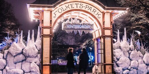 Entrén till Folkets Park i Malmö under Vinterdröm, dekorerad i ett vintrigt utseende. Två personer står framför entrén med en hund i ett koppel.