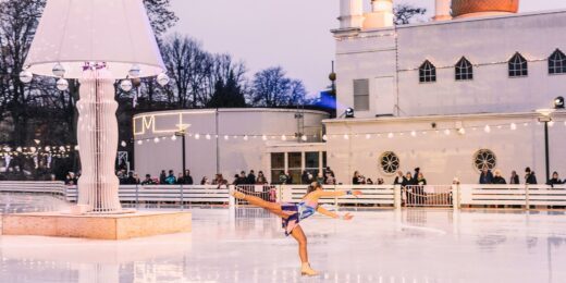 En person utövar konståkning på stora isbanan i Folkets Park, med Moriska Paviljongen i bakgrunden.