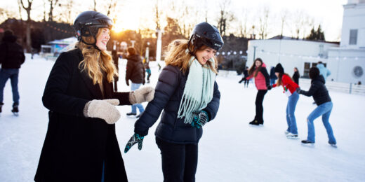 Två personer åker skridskor i Folkets Park. I bakgrunden syns flera personer som åker skridskor.