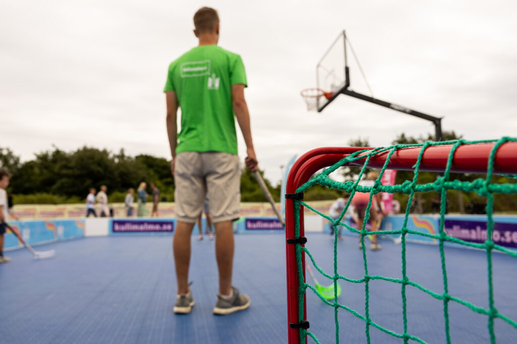 Person med en innebandyklubba. I bakgrunden syns en basketbollkorg.